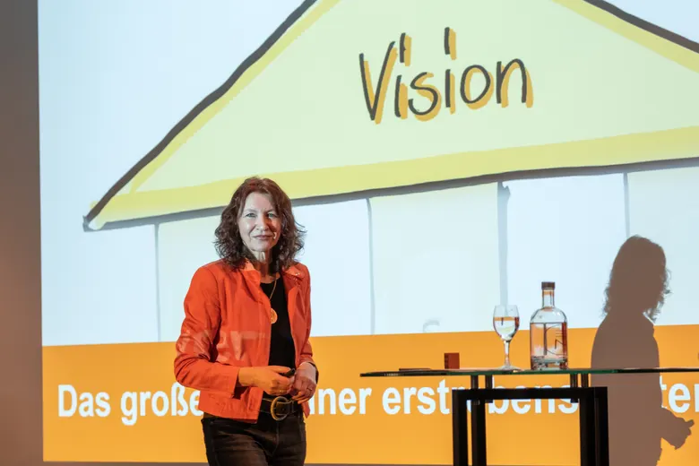 Silvia Ziolkowski auf der Bühne vor dem Dach des Zukunftshauses mit dem Wort „Vision“